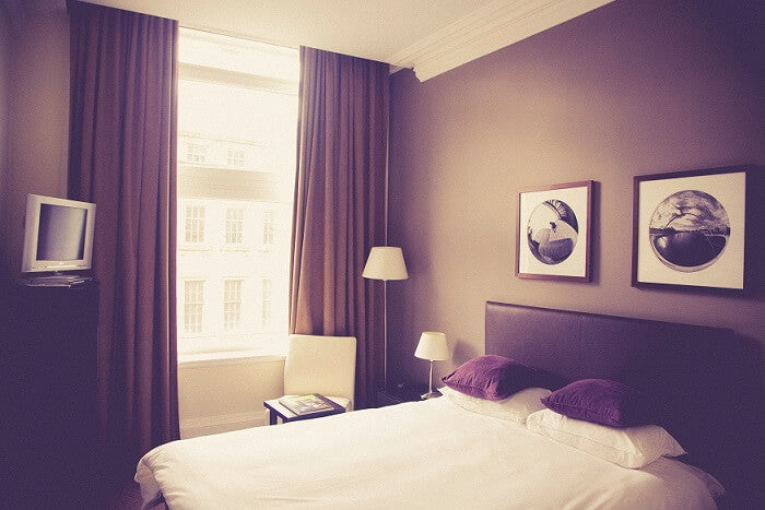 bedroom with white sheets and dark brown curtains