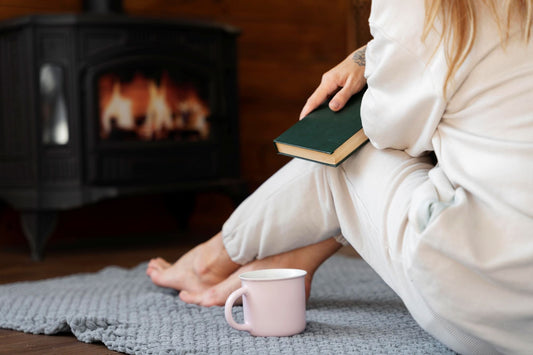 woman sitting in front of fire wearing pajamas