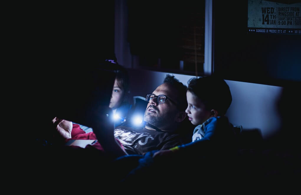 man reading bedtime stories to kids