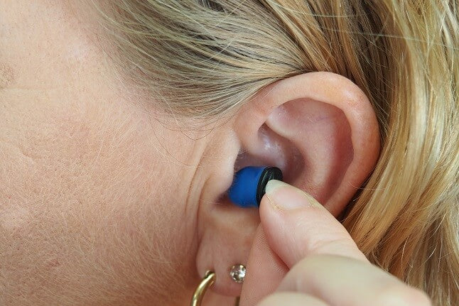 Woman putting an ear plug in her ear
