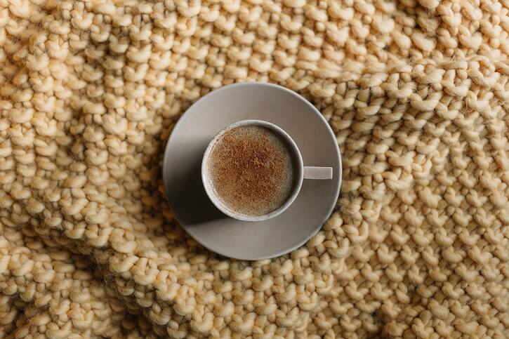 chunky light brown blanket with a cup of coffee