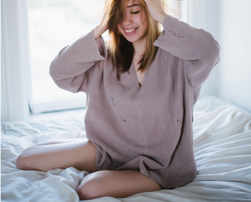 women wearing oversized sweater sitting on a bed
